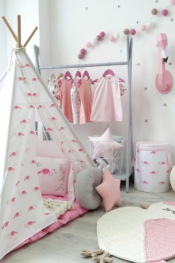 chambre enfant Montessori, lit cabane, tipi indien en tissu blanc aux flamants roses, tapis en rose et blanc en forme de grande poule cocon, murs peints en blancs aux pois argentés, couleur rose pale