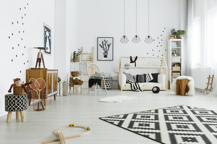 lit cabane montessori, cabane enfant lit en bois clair, petite taille, tapis aux losanges noirs et blancs, murs blancs aux pois noirs, étagère colonne blanche avec des paniers de rangement