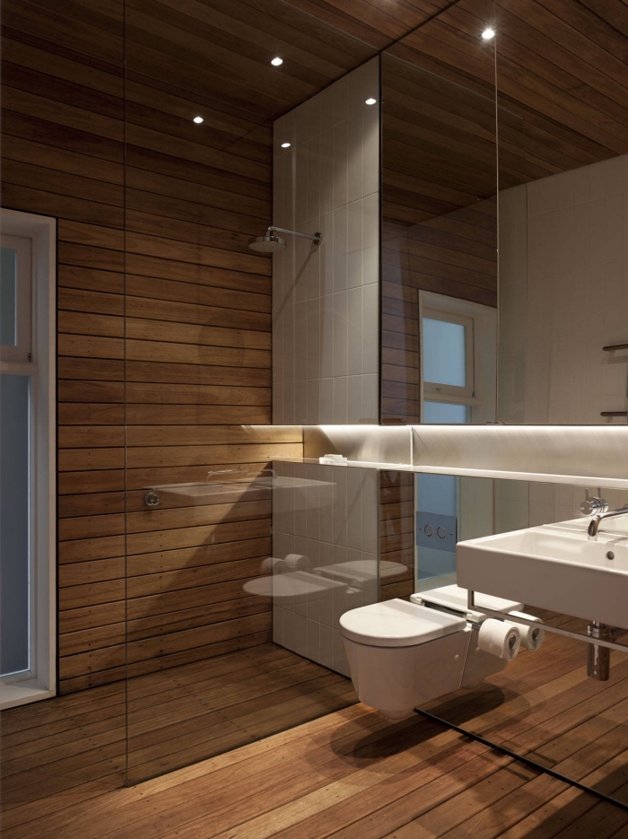 idée agencement petite salle de bain à revêtement imitation bois avec large miroir à rangement et cuvette wc suspendue