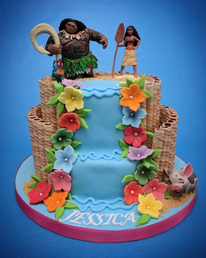 gateau vaiana à deux étages à design cascade d'eau décorée de fleurs en pâte à sucre colorées avec figurines Maui et Vaiana