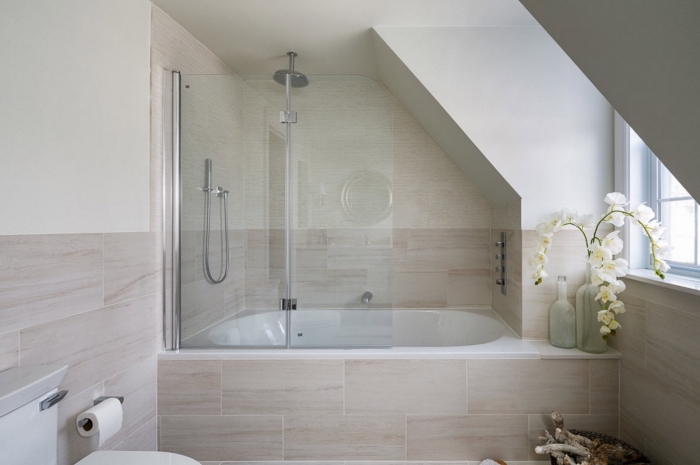 modèle de salle de bain mansardée au plafond blanc avec revêtement partiel en carrelage beige, salle de bain avec baignoire