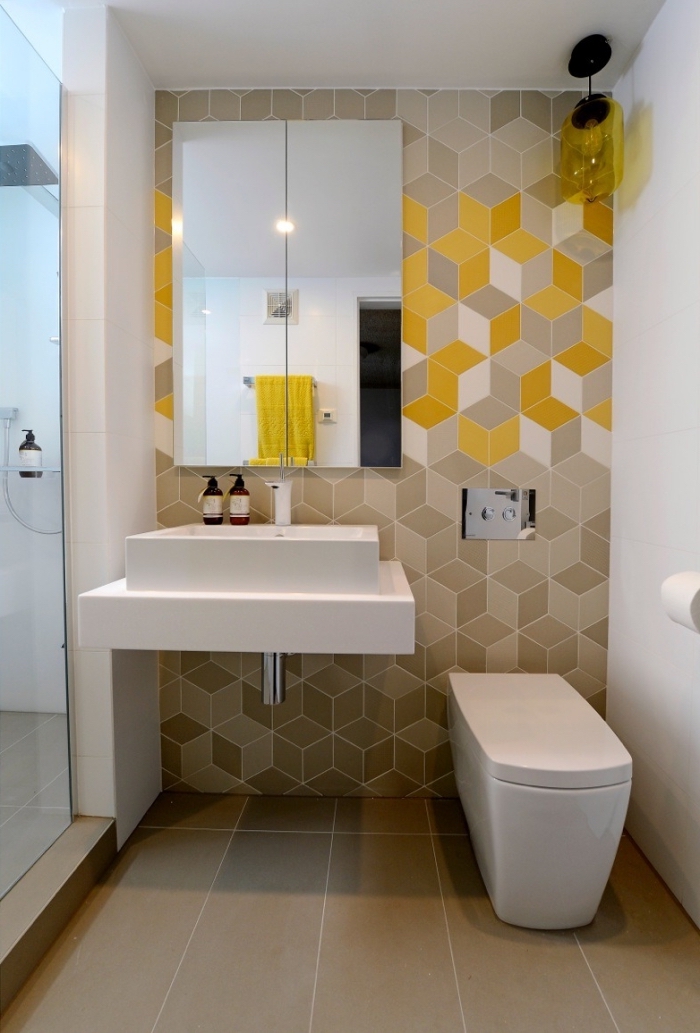 exemple de déco petit espace dans une salle de bain avec cabine de douche, revêtement mural en carrelage beige et jaune