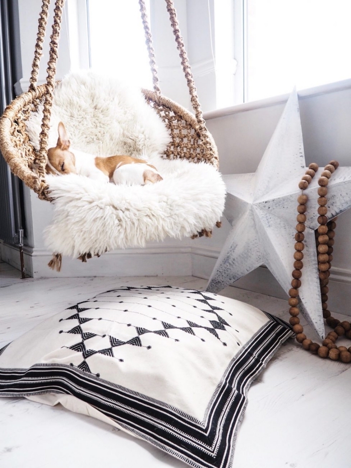 ambiance cozy dans une chambre aménagée de style boho avec chaise suspendue couvert de housse en fausse fourrure blanche