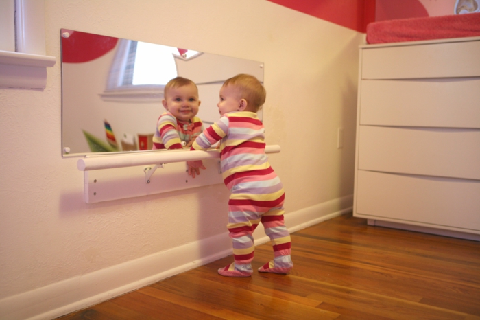 miroir sur un mur pour éveiller les sens de bébé, lit montessori dans une chambre montessori, lit bébé sans barreau, barre en blanc, pour aider les premiers pas de bébé 