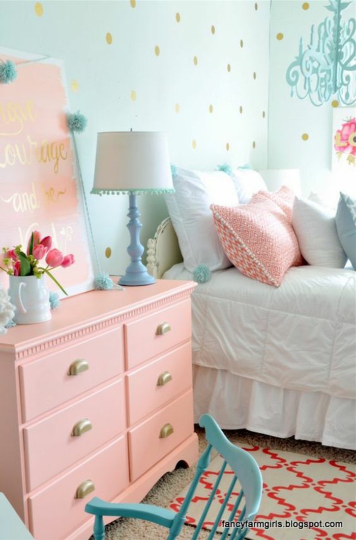 couleur rose poudré pour un meuble de rangement dans une chambre d'adulte, murs en papiers peints en bleu pastel aux pois dorés, luminaire lustre aux pampilles en bleu pastel 