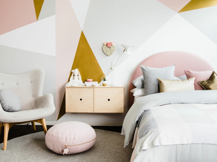 chambre d'adulte, murs aux motifs géométriques, tete de lit en peluche en couleur rose poudré, petit pouf rond avec fermeture éclair avec une étoile en tissu au bout, tapis rond beige