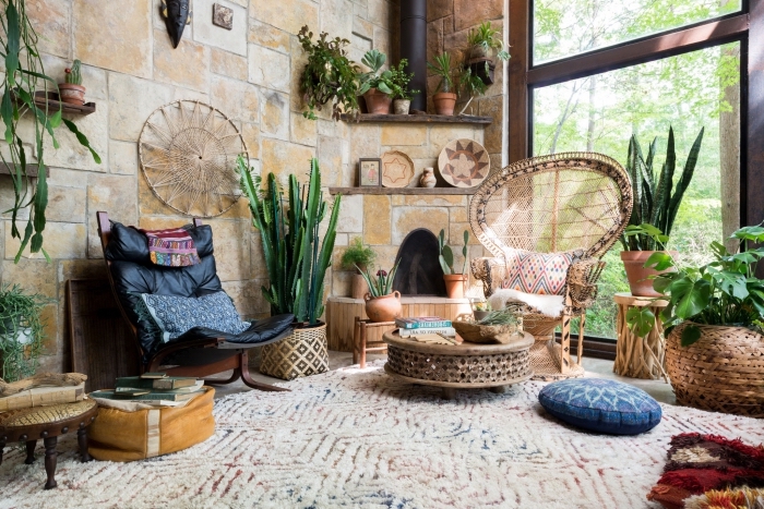 décor chic ethnique dans une pièce large aux murs en pierre avec étagères de bois foncé et chaises et table en rotin
