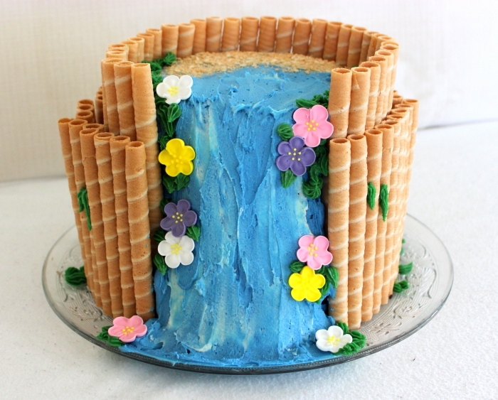decoration gateau vaiana à deux étages couvert de sable en biscuits émiettés et cascade d'eau en crème au beurre et colorant turquoise