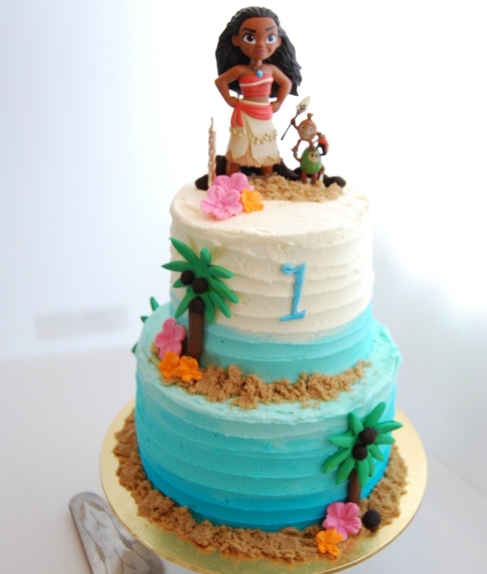 exemple de deco vaiana sur un gâteau à design océan en bleu et blanc avec figurines des personnages de Disney