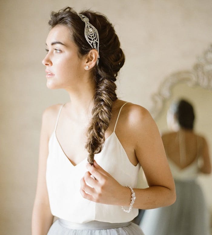 comment-faire-une-coiffure-mariage-tresse-épi-de-coté-avec-un-dessus-en-volume-et-un-bijoi-de-tete-debardeur-blanc-et-jupe-gris-clair tresse sur le coté femme cheveux chatain avec une diademe en pierres precieuses, volume sur le dessus