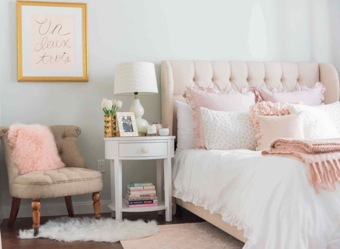 chambre rose poudré, tete de lit en couleur rose pale, petit fauteuil en tissu beige clair, tapis rose pale, rose poudree, tableau au cadre doré avec l'inscription en lettres dorées Un, deux, trois