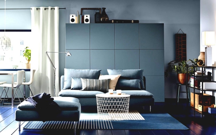 un canapé bleu canard assortie avec le meuble de rangement besta de même couleur bleu vert, ambiance sereine et apaisante dans un salon bleu vert aux accents blancs