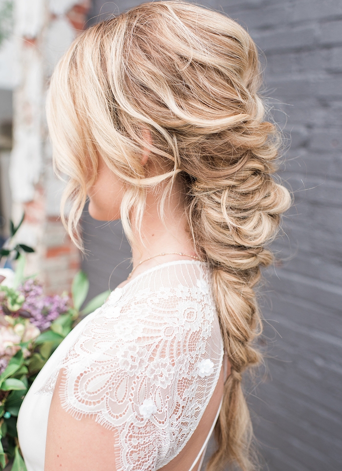 créer-une-tresse-columineuse-en-arrière-style-princesse-avec-des-mèches-libres-encadrant-le-visage-volume-sur-le-dessus-robe-de-mariée-dentelle tresse volumineuse avec des mèches encadrant le visage, cheveux longs blond, robe de mariée dentelle