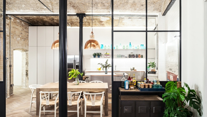cuisine et salle à manger style industriel, deux lampes cuivrées suspendues, un mur blanc avec mur briques et plafond en béton
