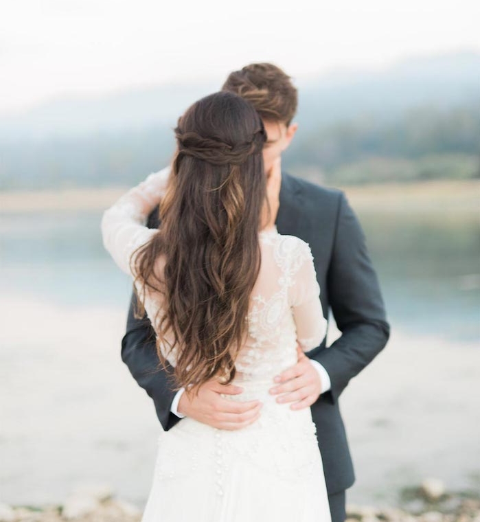 demie-couronne-de-tresses-deux-petits-tresses-qui-passent-en-arrière-de-la-tête-et-cheveux-longs-lachés-chatain-robe-de-mariée-haut-en-dentelle exemple de couronne tresse avec les mèches de côté sur cheveux chatain longs ondulés, robe de mariée manche longue