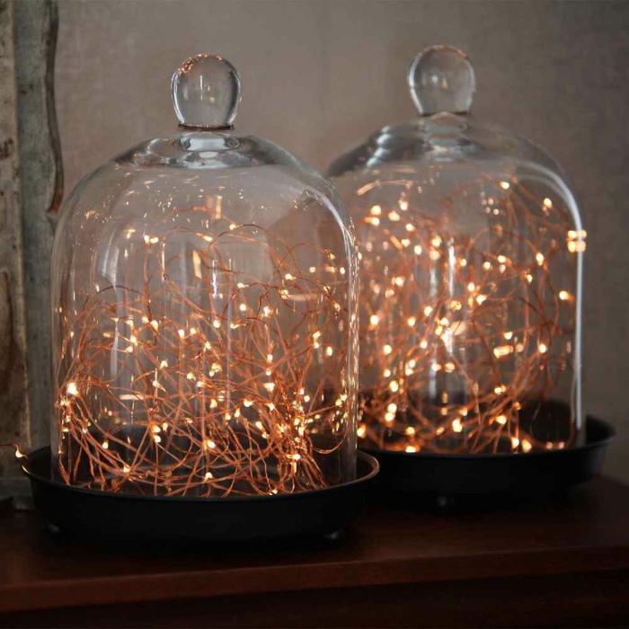 deux guirlandes posées dans deux bocaux en verre, guirlande lumineuse ampoule, installations sur une lampe de chevet, guirlande lumineuse interieur