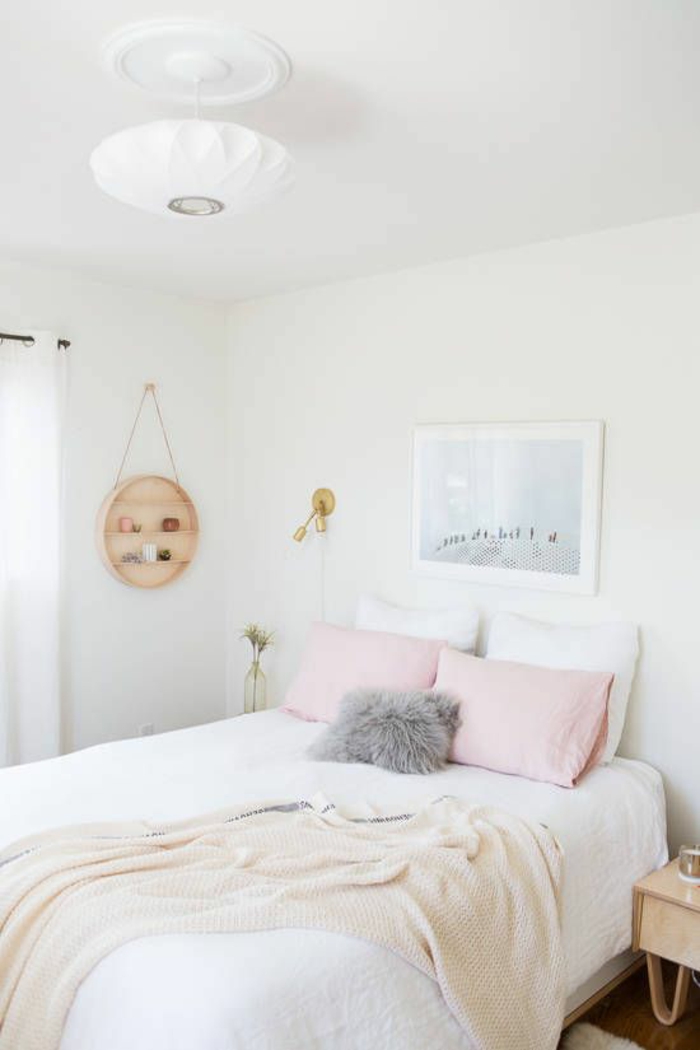 chambre d'adulte, deux grands coussins en couleur rose poudré, plafond blanc avec plafonnier en verre mat blanc, tableau avec paysage marin au cadre blanc au-dessus du lit