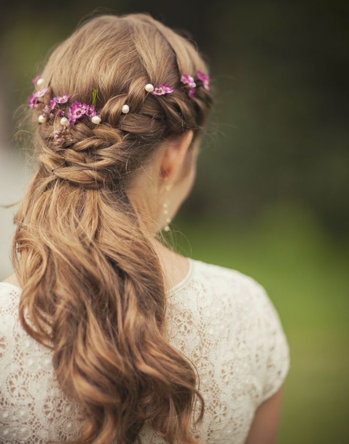 deux-tresses-laterales-qui-se-croisent-en-arrière-avec-des-petites-fleurs-mauve-robe-de-mariée-dentelle-manche-courte deux tresses latérales ramenés en arrière, racines tressées, longueurs lâchées, petites fleurs mauves décoratives