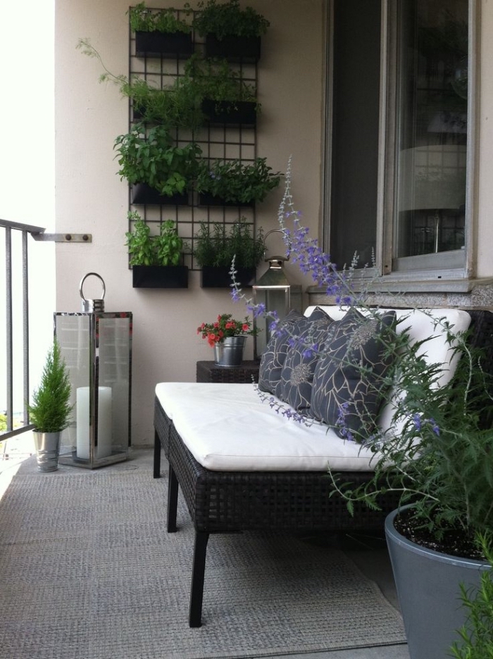 idée pour créer un jardin vertical dans un petit balcon, des pots noirs fixés sur une grille métallique 