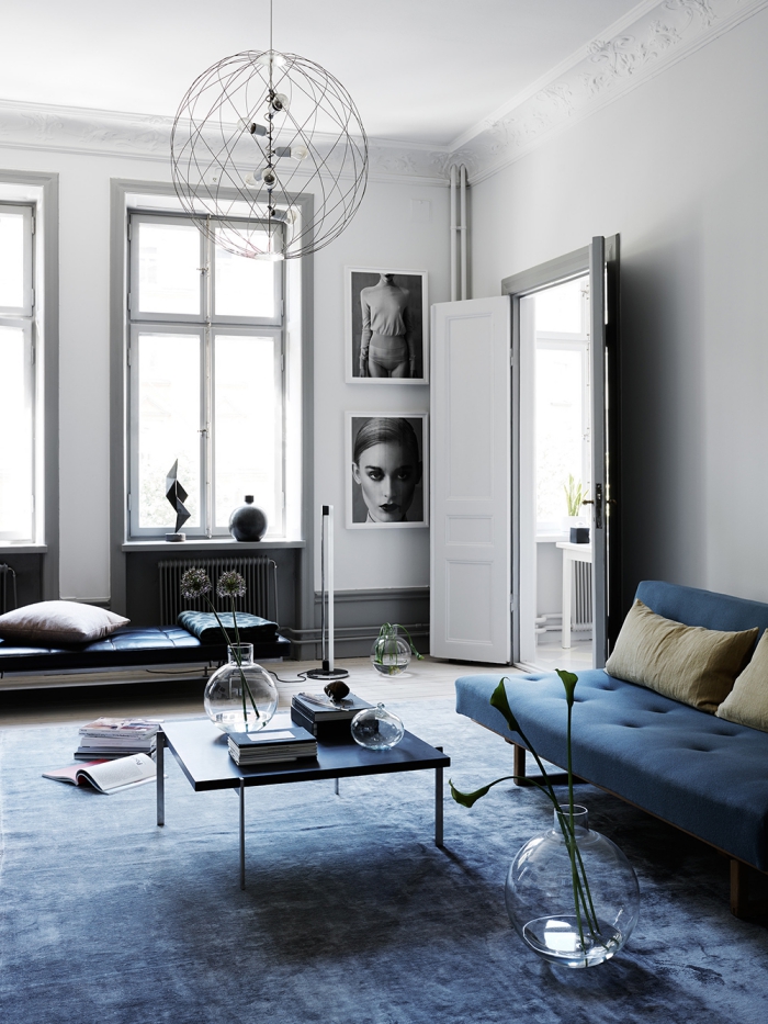 déco salon style minimaliste en bleu, blanc et gris avec des meubles aux lignes épurées, un canapé bleu marine de même couleur que le tapis