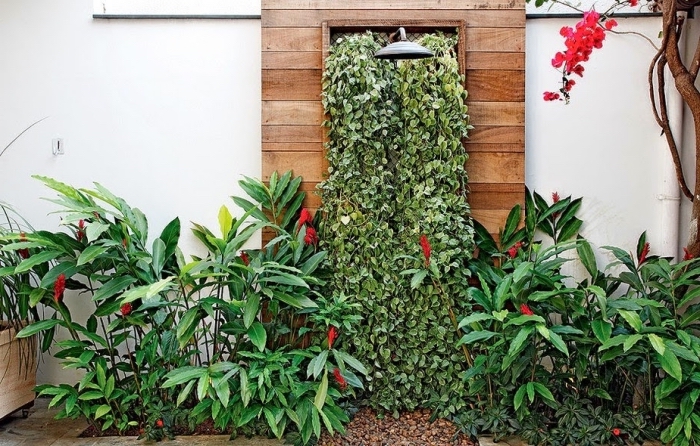 un coin de fraîcheur d'été aménagé dans le jardin avec une douche extérieur et un mur végétalisé aménagé derrière