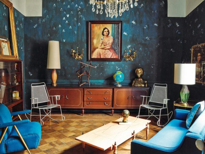 petit séjour artistique, canapé et fauteuil bleu style mid century, buffet bas, lampadaires vintage, plafonnier pampilles