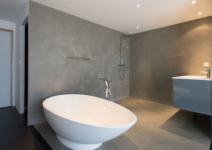 enduit béton ciré pour murs de salle de bain ouverte avec douche italienne et baignoire ilot