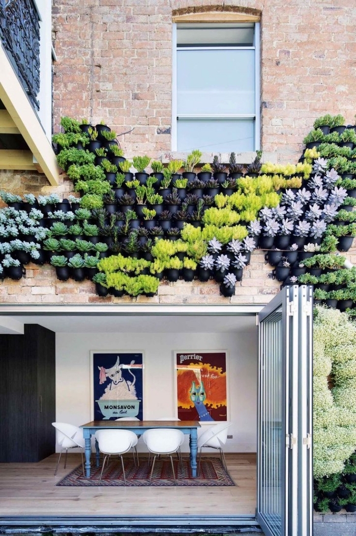 une façade végétalisée composée d'une multitude de pots fixé au mur, en-dessus de la porte de la véranda
