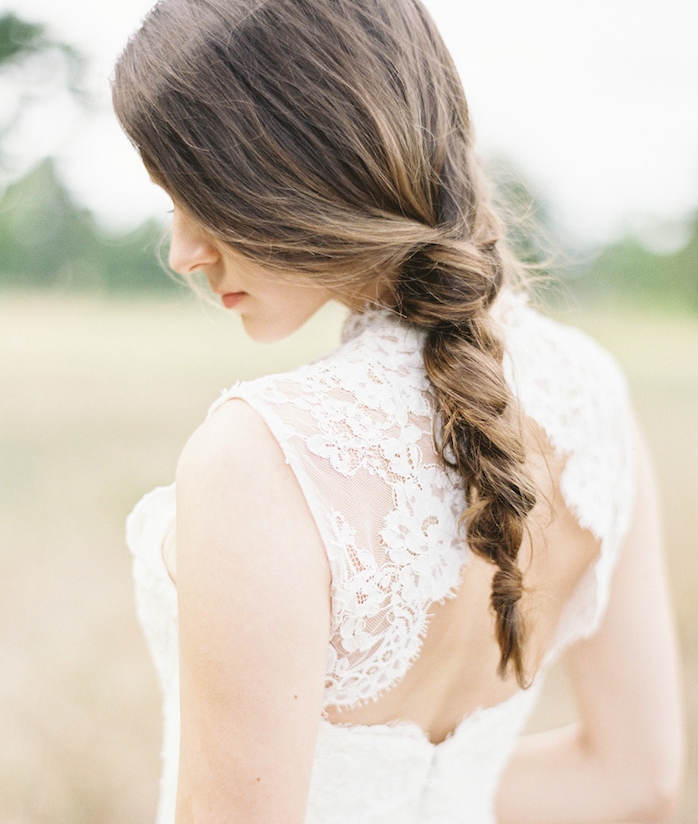 femme-à-la-robe-de-mariée-dentelle-avec-une-tresse-floue-style-décoiffé-cheveux-chatain-clair exemple de coiffure tresse mariage tresse floue desserée sur l arrière de la tête, robe de mariée dentelle