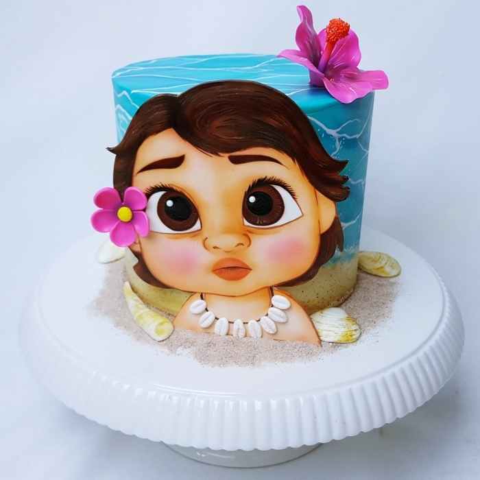 ideé deco vaiana sur un gâteau Disney réalisée avec fondant turquoise et blanc, modeler le visage bébé vaiana en fondant et colorants alimentaires