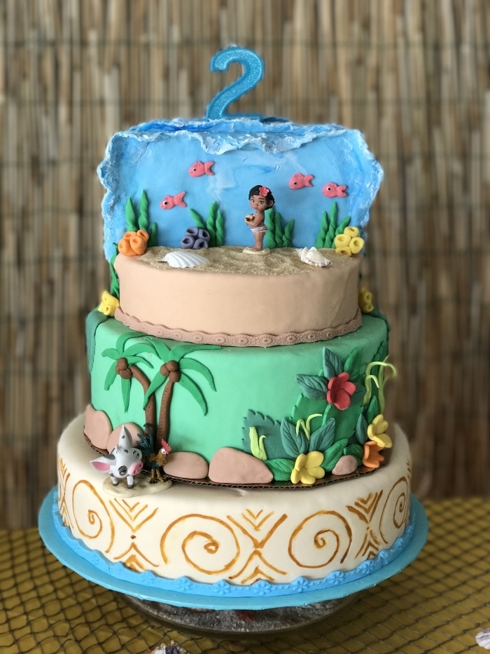 exemple de magnifique gâteau fait maison sur le thème Vaiana à trois étages avec étage sable et nature en fondants colorés