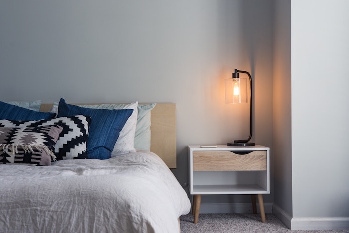Simplicité et confort dans une chambre à coucher scandinave style, lampe sur la table de chevet retro en bois 