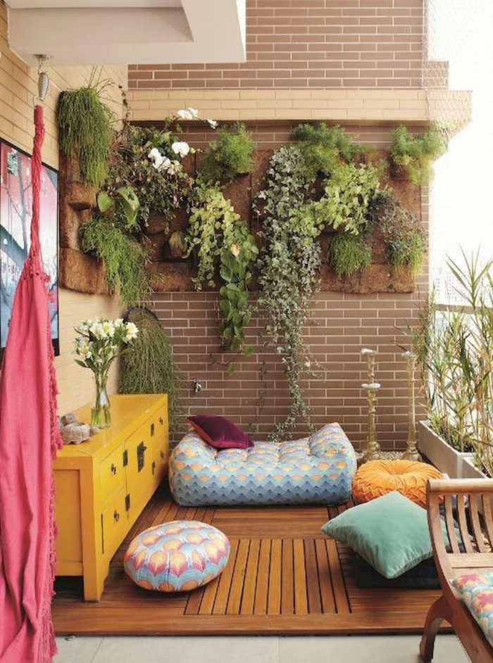 idée originale pour l'aménagement d'un mur végétalisé en fibre de coco, déco de balcon bohème chic avec des poufs et des coussins colorés