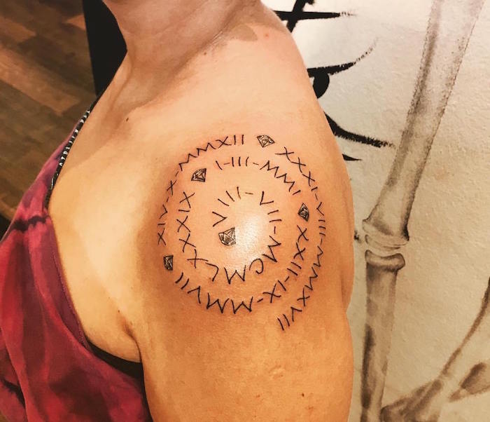 tattoo femme sur épaule spirale avec dates en chiffres romains et diamants