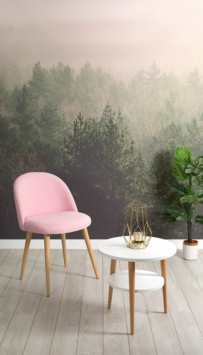fauteuil en couleur rose poudré aux pieds en bois clair, murs revêtus de papier peint aux images paysages forets, chambre rose et gris, table deux niveaux petit et grand, deux plans blancs, parquette en beige clair