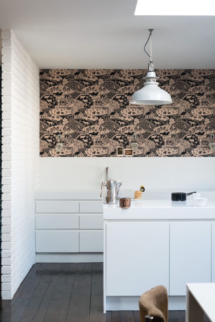 cuisine blanche au design épuré et minimaliste réveillée par du papier peint deco tendance à motif paysage posé en haut du mur