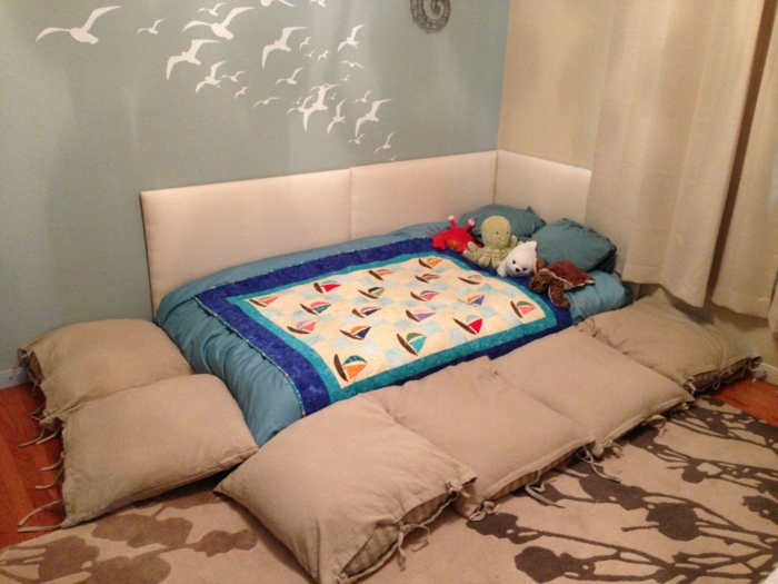 lit montessori cabane, espace pour dormir, lit de bébé, murs couleur vert d'eau, tapis marron avec des silhouettes beiges de fleurs et de plantes 