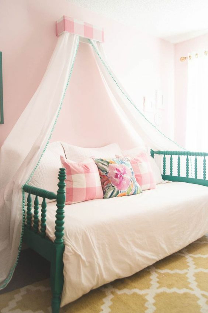 chambre adolescent avec grande moustiquaire en tissu couleur rose pale, tapis moutarde aux losanges blancs, lit avec des barreaux en bois peint en vert aux deux extremités