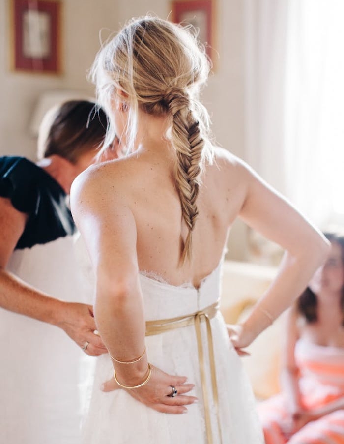modèle-de-coiffure-bohème-pour-mariage-avec-une-tresse-épi-simple-et-des-mèches-rebelles tresse épi en arrière de la tête avec des mèches libres rebelles, robe de mariée simple, ruban or