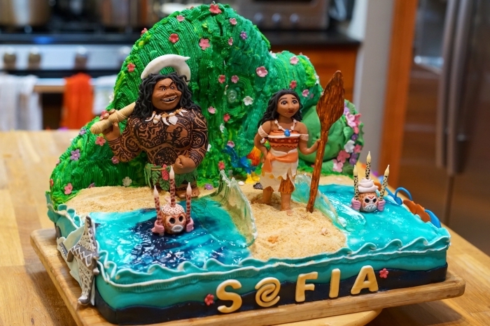 jolie idée pour un gâteau d'anniversaire enfant sur le thème Vaiana avec figurines des personnages et à design nature et océan
