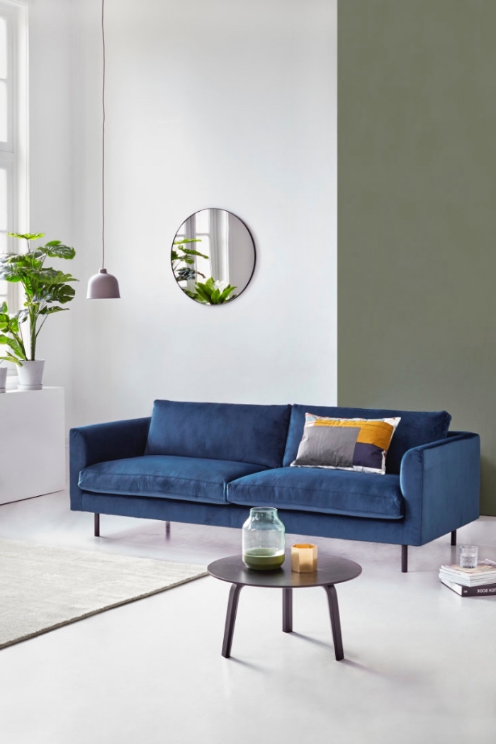ambiance naturelle et apaisante dans un salon blanc, vert et bleu, canapé bleu marine design met en valeur par un coussin imprimé gris, jaune moutarde et bleui indigo