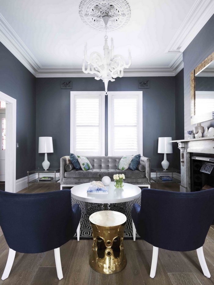 la couleurs bleu nuit des murs et des fauteuils s'associe aux éléments déco en blanc et gris pour donner à ce salon vintage un aspect élégant et chic