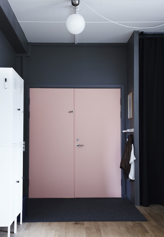 une porte d'entrée repeinte en rose poudré qui crée une ambiance moderne et chic dans l'entrée grâce à l'association au bleu nuit des murs