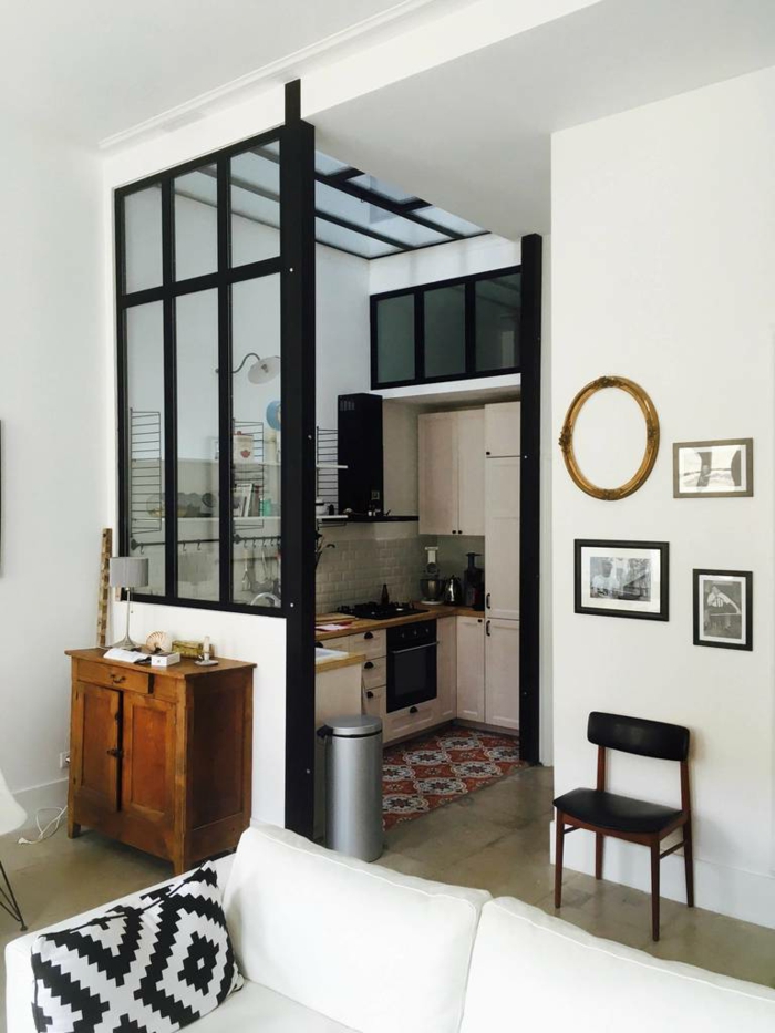 petite cuisine en l avec cloison vitrée noire style atelier d'artiste, buffet en bois rustique, grand sofa blanc, coussin géométrique