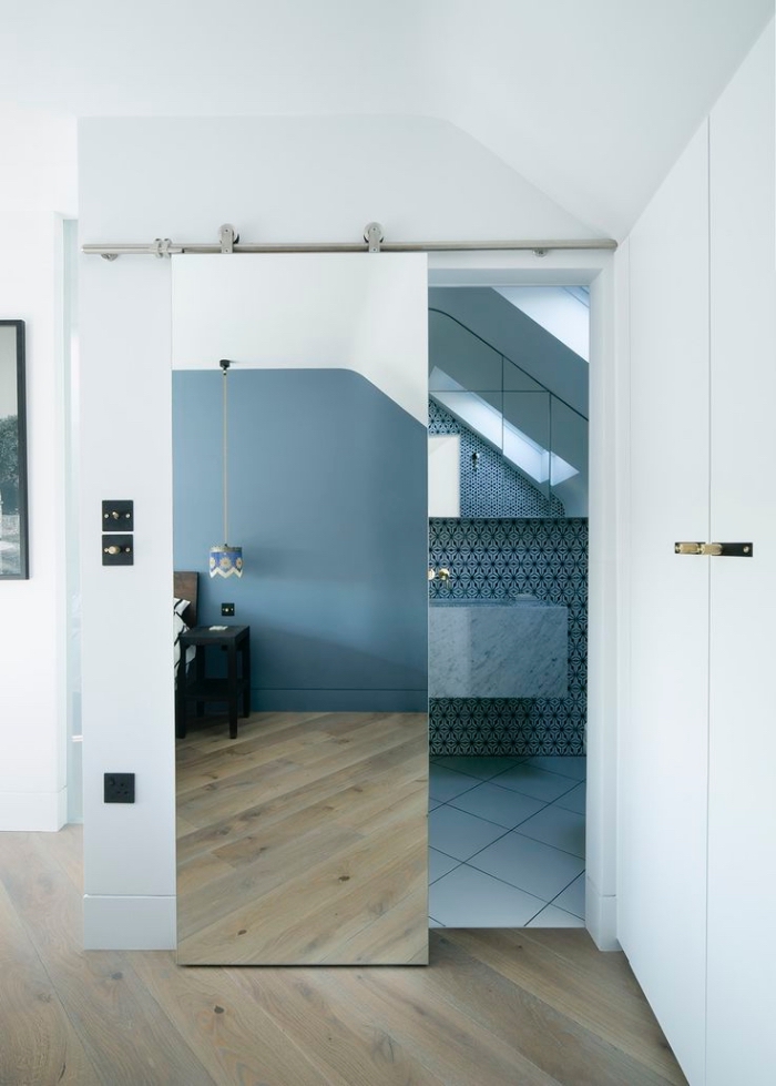 une porte de salle de bains coulissante belle et pratique, recouverte de miroir pour donner une sensation de profondeur dans la chambre à coucher adjacente, recouvrir porte interieure de miroir