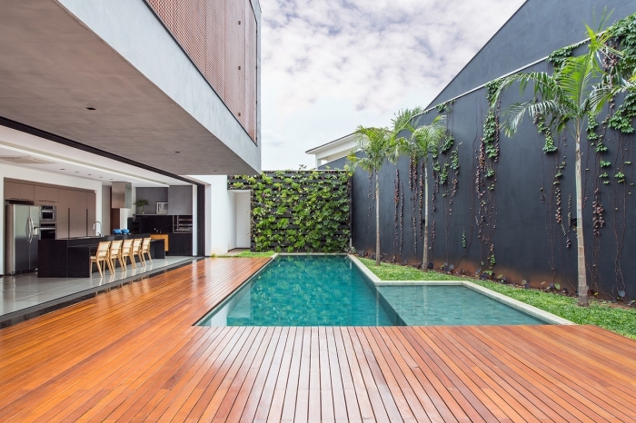 une piscine de luxe avec terrasse de bois, cuisine d'extérieur ouverte et un mur végétal extérieur 