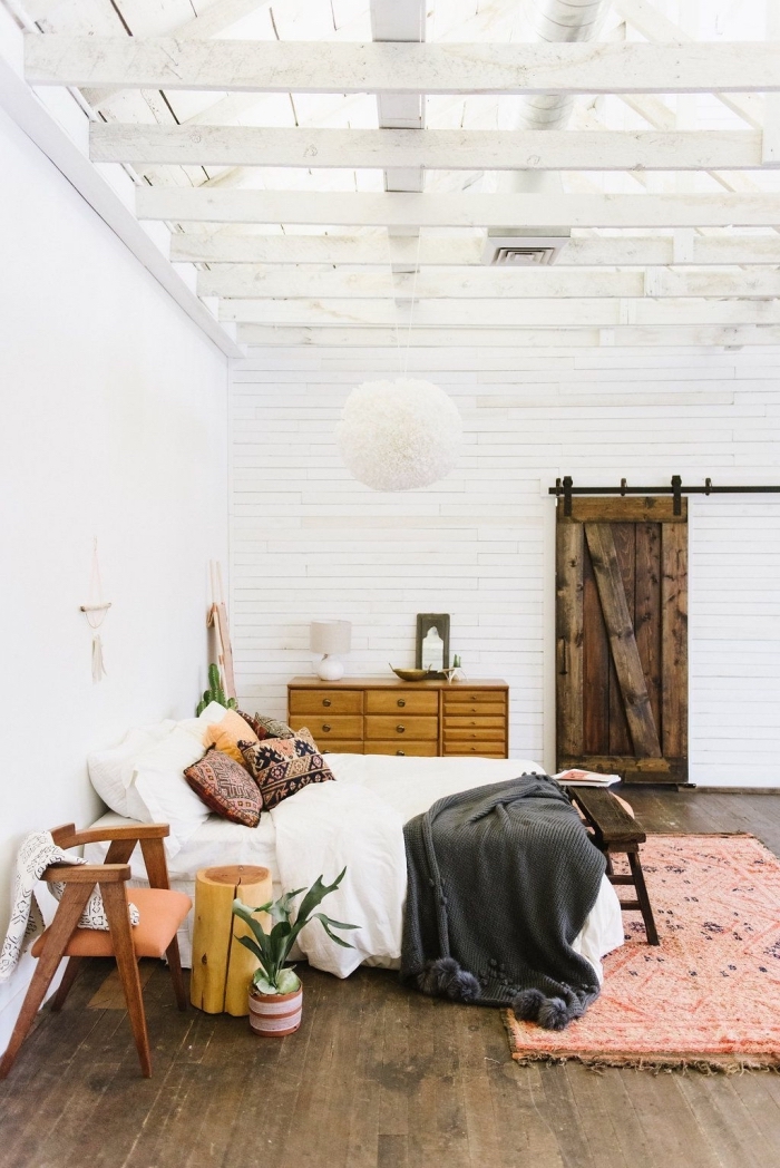 idée aménagement de chambre à coucher en style bohème avec meubles de bois, pièce au plafond haut avec poutres de bois blanc