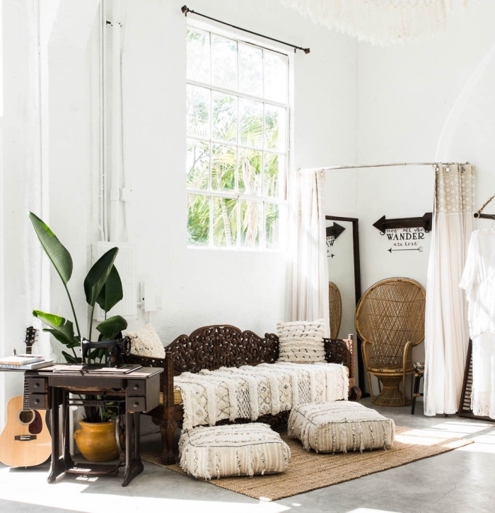 pièce de style bohème chic aux murs blancs et plancher design béton couvert de tapis beige et coussins bèrberes