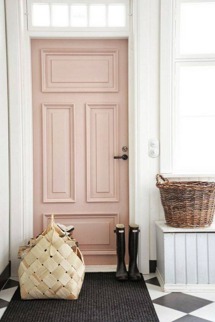 porte rose poudree, murs blancs, tapis noir, bottes en caoutchouc noir, deux grands paniers pour ranger ses affaires, carrelage en noir et blanc, motifs losanges
