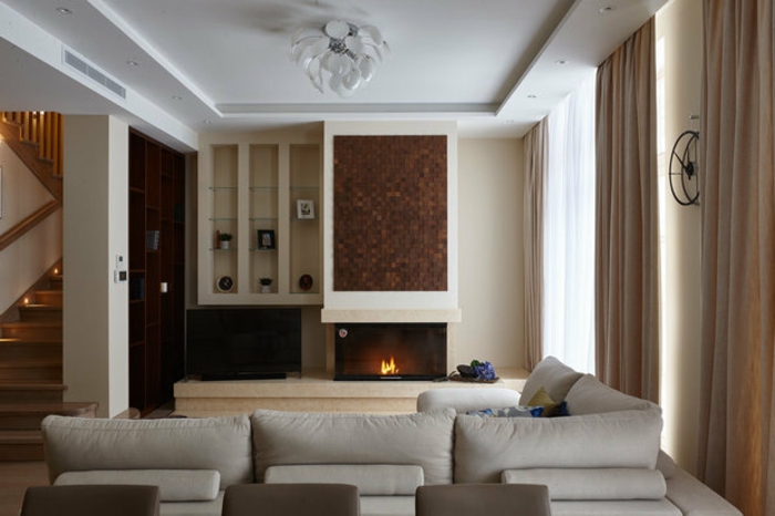 grand salon confortable, grand canapé d'angle, plafond blanc, cheminée murale